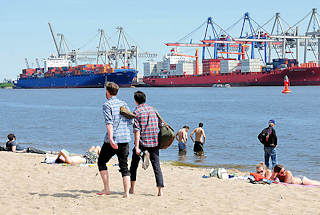 7305 Elbufer in Hamburg Othmarschen - Spaziergnger barfuss im Sand, ander stehen im Wasser oder sonnen sich im Elbsand; im Hintergrund Containerschiffe am Terminal Burchardkai.