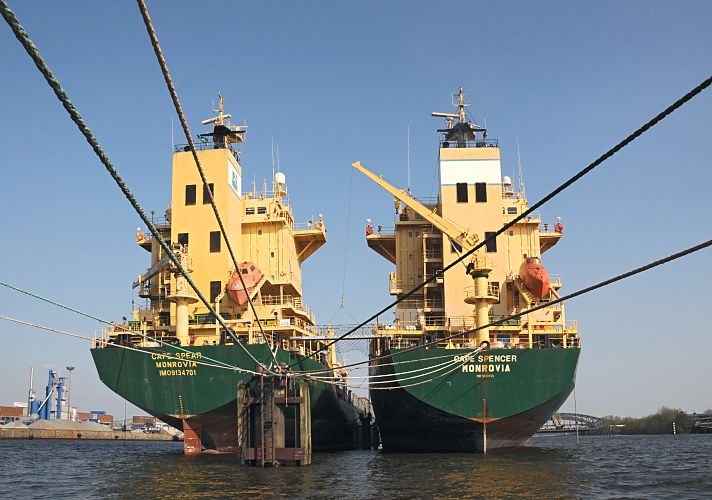 Schiffsfotos von Aufliegern auf der Hamburger Norderelbe //  Elbbrcken  011_42-6017 Heckansicht aufgelegter Containerfrachter auf der Hamburger Norderelbe, im Hintergrund die Hamburger Elbbrcken. Der Container Transport ist aufgrund der weltweiten Wirtschaftskrise stark zurck gegangen. Aus diesem Grund werden Frachtschiffe stillgelegt; bei einer "heissen" Stilllegung wird das Schiff nur fr eine begrenzte Anzahl von Wochen deaktiviert -  dies geschieht mit einer kleinen Besatzung und kontinuierlicher Maschinenaktivitt. So kann das Schiff in relativ kurzer Zeit wieder in Betrieb genommen werden. Bei einer "kalten" Stilllegung wird das Schiff fr lngere Zeit "vom Markt" genommen, eine Reaktivierung ist dann recht langwierig und kann bis zu drei Monaten dauern. www.hamburg-fotograf.com 