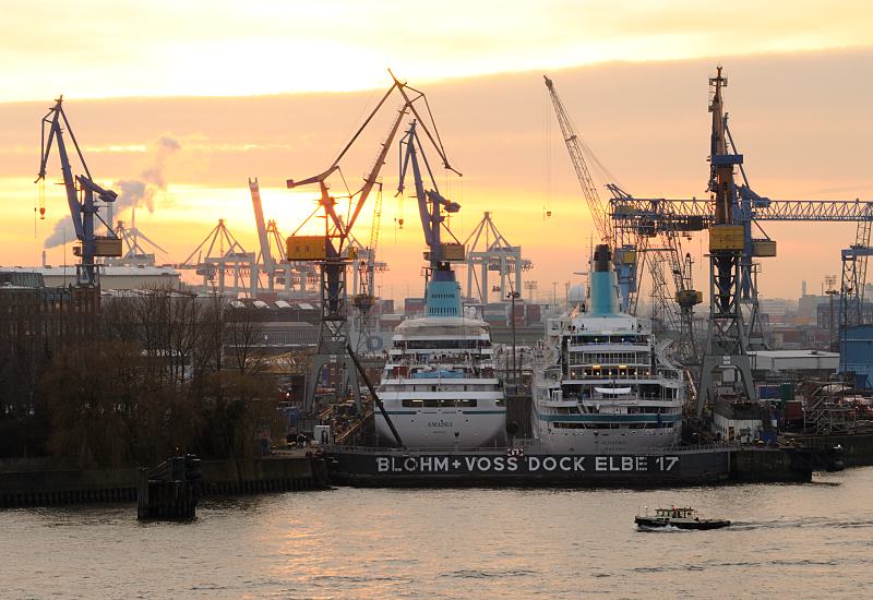 Hafenfotos aus der Hamburg - Kreuzfahrtschiffe eingedockt auf der Werft Blohm + Voss. - Fotograf Christoph Bellin.  011_65_4357 Die Passagierschiffe AMADEA und ALBATROSS liegen nebeneinander im Trockendock Elbe 17 der Hamburger Werft Blohm + Voss. Hinter den Hafenkrnen geht die Sonne unter, eine Barkasse fhrt auf der Elbe Richtung Reiherstieg. 