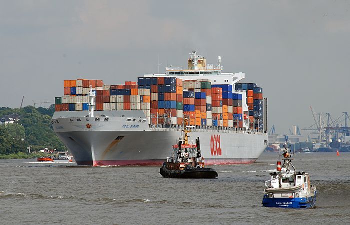 011_26055  Der Containerriese OOCL EUROPE verlsst hoch mit Containern beladen  den Hamburger Hafen - das 2006 gebaute Frachtschiff fhrt fr die Orient Overseas Container Line und kann mehr als 8000 TEU / Standart Container transportieren. Im Hintergrund die Hafenanlagen des Hamburger Hafens, rechts das Polizeiboot AMERICAHFT der Hamburger Wasserschutzpolizei.   www.christoph-bellin.de