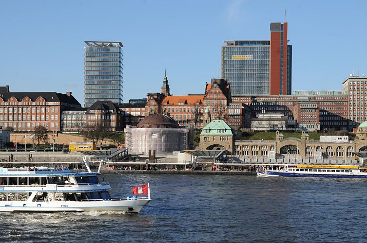 Bilder der Hamburger Sehenswrdigkeiten - St. Pauli Landungsbrcken + Alter Elbtunnel  011_26070ein Fahrgastschiff hat Hamburg-Touristen an Bord, denen der Hamburger Hafen, die Speicherstadt und die Riesenbaustelle der zuknftigen Hamburger Hafencity gezeigt wird - die Hamburger Flagge weht im Fahrtwind am Bug des weissen Schiffs. Im Hintergrund die Pontonanlage der St. Pauli Landungsbrcken und die Kuppel vom Eingang zum Alten Elbtunnel. Dahinter die historische Architektur von der Navigationsschule und lks. das Gebude vom Tropeninstitut. Das Hafenpanorama ist durch moderne Neubauten erweitert worden. www.christoph-bellin.de