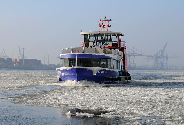 Fotos vom Hamburger Hafen im Winter - Hafenfhre zwischen Eisschollen auf der Elbe  011_26073 Winter in Hamburg- eine Hafenfhre kommt von Hamburg Finkenwerder und fhrt durch den Eisgang auf der Elbe Richtung St. Pauli Landungsbrcken. Im Hintergrund sind die Containerbrcken vom Containerterminal Predhlkai zu erkennnen. www.hamburg-fotograf.com