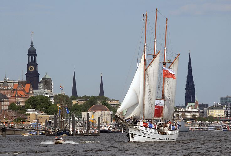 Hamburgfoto vom Panorama der Hansestadt - Kirchtrme der Hamburger Hauptkirchen.  011_26079 Hamburg Panorama mit Kirchtrmen der Hansestadt Hamburg - links der Michel, dann der Turm der St. Petrikirche, danach die St. Jakobikirche, rechts die hohe Turmruine der St. Nikolaikirche die als Mahnmal stehen gelassen wurde - davor der kleine Turm der Gustav-Adolf-Kirche. Im Vordergrund der 1907 in Norwegen gebaut Heringslogger LOTH LORIEN unter Segeln. www.hamburg-fotograf.com