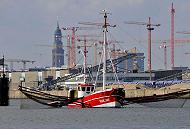 011_26068 das Fischerboot LUISE /HBK 103 aus Hamburg Finkenwerder fischt auf der Elbe vor den Elbbrcken; links und rechts werden ber Ausleger die Netz ins Wasser gelassen. Das Fischereiboot ankert im Strom und bei abfliessendem Wasser / Ebbe werden die Fische gefangen. Im Hintergrund Baukrne, die auf den Baustellen der Hamburger Hafencity stehen - dahinter das Wahrzeichen Hamburgs die St. Michaeliskirche. Die Hamburger Hauptkirche ist einer der Sehenswrdigkeiten fr Hamburg-Touristen und wird von den Einwohnern der Hansestadt auch liebevoll "Michel" genannt.   www.christoph-bellin.de