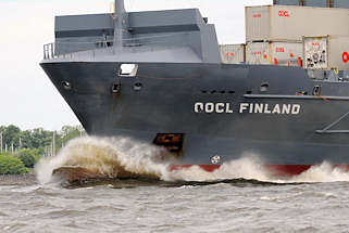 8932 Frachtschiff OOCL FINLAND in Fahrt auf der Elbe - Gischt schäumt am Schiffsbug.