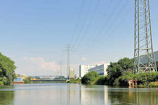 5867 Hochspannungsleitungen, Hochspannungsmasten entlang des Tidekanals in Hamburg Billbrook; im Hintergrund die Brücke der Moorfleeter Strasse.