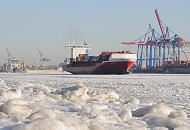 011_81_5775 Der Elbstrand ist mit dicken Eisschollen bedeckt. Ein Frachtschiff verlsst durch das dichte Treibeis den Hamburger Hafen - am Containerterminal Buchardkai werden Frachter be- und entladen. Im Hintergrund kommt ein Container Feeder aus dem Khlbrand. 