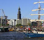 011_26080 die Barkentine Atlantis vor den Hamburger Landungsbrcken mit der St. Michaeliskirche als Wahrzeichen Hamburgs. Die jetzige Windjammer ist bis in die 1980er das Feuerschiff ELBE 2 gewesen und wurde dann zu einem Passagierschiff umgebaut. Links ein Ausschnitt der Rickmer Rickmers unter Flaggen. www.hamburg-fotograf.com