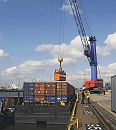 011_26097 Mit einem mobilen Kran wird im Hansahafen am O'swaldkai ein Container auf einen Schubleichter verladen; der beladene Leichter (auch Barge genannt) wird mit einem Schubschiff an seinen Bestimmungsort gebracht. www.hamburg- fotograf.com