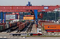 011_15671 Blick auf den Gterbahnhof vom Container Terminal Altenwerder; im Vordergrund ein leerer Lastzug; grosse Bahnkrne berspannen die Bahngleise und beladen die einzelnen Waggons mit ihrer Containerfracht. Der Bahnkran transportiert den Container vom Transportchassis zum Gterzug.