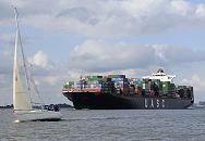 011_26056  Das ca. 300m lange und 40m breite Containerschiff AL BAHIA auf der Elbe - mit knapp 7000 TEU / Containern Fracht hoch beladen fhrt es Richtung Hamburger Hafen. Im Vordergrund ein Segelschiff im Wind.  www.christoph-bellin.de