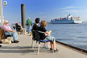 Schiffsanleger Hamburg Teufelsbrck - Menschen sitzen auf Sthlen in der Sonne und beobachten den Schiffsverkehr auf der Elbe. Bilder aus den Hamburger Stadtteilen und Bezirken - Fotos aus Hamburg NIENSTEDTEN, Bezirk Hamburg ALTONA. 1297 wurde das Dorf Nienstedten erstmals urkundlich erwhnt. Die Verwaltung ab 1350 in Pinneberg. Durch den deutsch-dnischen Krieges von 1864 kam Nienstedten zu Preuen. Die Zeit der Zugehrigkeit zu Pinneberg fand 1927 ihr Ende, als der Ort durch das Gro-Altona-Gesetz zur Stadt Altona kam. Durch das Gro-Hamburg-Gesetz fiel es 1937/1938 gemeinsam mit Altona und anderen Stadtteilen an Hamburg. Der Stadtteil Nienstedten hat eine Flche von 4,3 km und ca. 7 000 Einwohner.