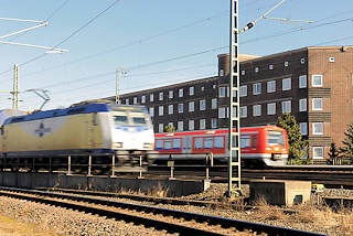 2920 Fahrender Metronomzug und  S - Bahn auf den Gleisen auf der Veddel - Bahnstrecke am Wohngebiet; Klinkerhuser auf der Hamburger Veddel.