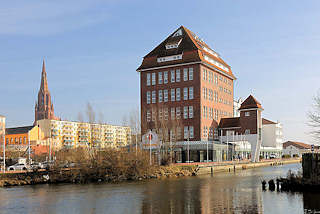 7372 Ehem. Speichergebude im Hafen der Hansestadt Demmin; umgebaut zum Geschfts- und Brogebude; im Hintergrund mehrstckige Plattenbauten und der Kirchturm der St. Bartholomaeikirche.