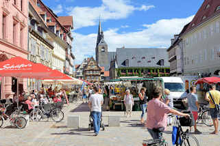 100_2827 Wochenmarkt am Marktplatz von Quedlinburg - Verkaufsstnde mit Obst und Gemse; Cafs und Restaurant mit Tischen auf der Strasse - Gste sitzen unter Sonnenschirmen in der Sonne; im Hintergrund das Rathaus und die Marktkirche / St. Benedikt Kirch