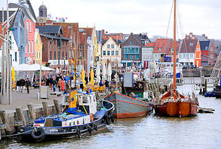 0726 Binnenhafen von Husum - ehem. Werfthafen - Promenade mit Touristen und farbigen Hausfassaden - Schiffe am Kai.