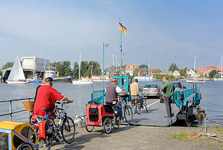3897 Autofhre / Personenfhre - Seilfhre ber die Schlei bei Arnis, Schleswig Holstein. Fahrradfahrer mit Anhnger fahren auf die Seilfhre ber die Schlei - im Hintergrund die Stadt Arnis.