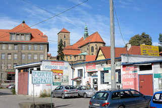 77_2853 Rckseite, Kirchenschiff der Katholische Pfarrkirche Mari Himmelfahrt - Kościł Wniebowzięcia Najświętszej Maryi Panny in Glatz / Kłodzko - errichtet ab 1390. Autowerkstatt mit bunten Schildern.