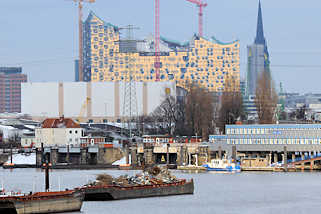 2727 Blick ber den Travehafen in Hamburg Steinwerder - beladene Schuten liegen an Dalben - lks. die Ellerholzschleuse, rechts Gebude der Wasserschutzpolizei; im Hintergrund Baustelle der Elbphilharmonie und Turm der St. Nikolaikirche.