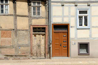 270_3536 Alt + Neu, restauriertes Fachwerkhaus mit blau abgesetzten Fenstern und Fachwerkbalken, neue Holztr mit Briefksten - altes FAchwerkhaus mit  vernagelten Fenster und alter Holztr, abgebltterte Farbe. Architektur in Halberstadt.