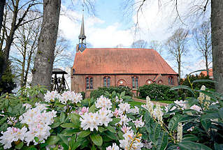 8798 St. Johannes Kirche in Seester; Patronatskirche Kloster Uetersen; sptgotische Bau, Ursprung im 15. Jahrundert. Dachreiter mit kleiner Glocke - freistehender Glockenstuhl aus Holz - blhender weisser Rhododrendron.