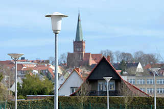 9852 Laternen / Lampen auf einem Parkplatz in Bergen - im Hintergrund der Kirchturm der St. Marien-Kirche in Bergen auf Rügen.