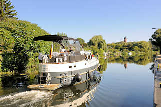 8794 Motorboot in Fahrt auf der Müritz - Elde - Wasserstrasse in Lübz; im Hintergrund der alte Wasserturm der Stadt.