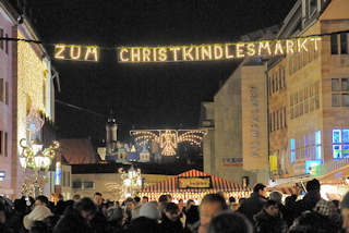 2242 Leuchtschild "Zum Christkindlesmarkt" - Menschengedränge; im Hintergrund die beleuchtete Burg von Nürnberg.