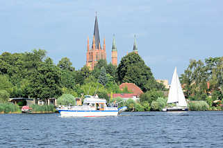 1694 Blick vom Wasser über die Havel zur Heiligen Geist Kirche der Stadt Werder; ein Segelboot fährt auf dem Fluss.